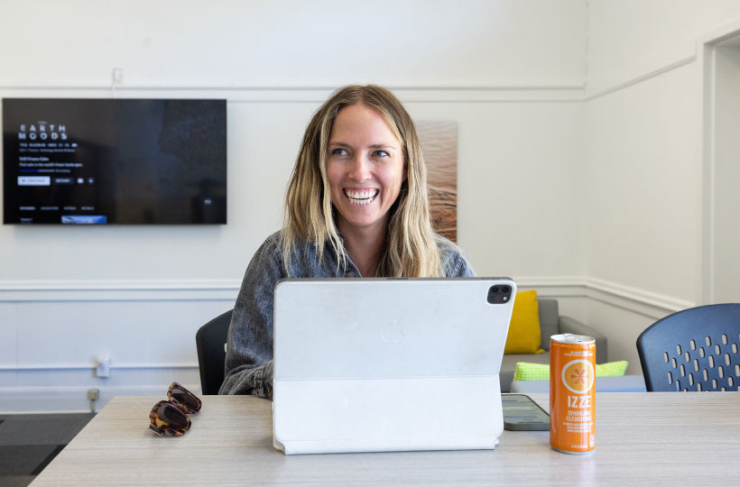 woman smiling while working in front of laptop